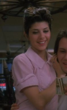 a woman holding onto another woman's shoulder while she smiles at the man in the pink shirt