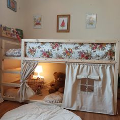 a teddy bear sitting in the bottom bunk of a loft bed with curtains on it