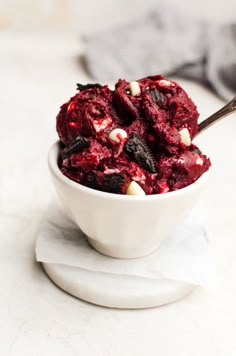 a bowl filled with red velvet cookies and marshmallows next to a spoon