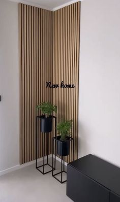 two black planters sitting next to each other in front of a wall with vertical blinds