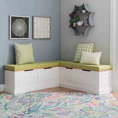 a corner bench with two pillows on it in a living room next to a blue wall