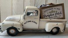 an old white truck with a dog sitting in it's bed and a sign that says autumn acres pumpkin patch