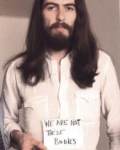 a man with long hair and beard holding a sign that says we are not the s e bodies