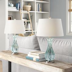 two lamps sitting on top of a wooden table next to a couch in a living room