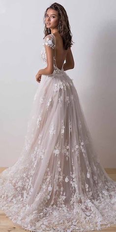 a woman in a wedding dress standing on a wooden floor with her back to the camera