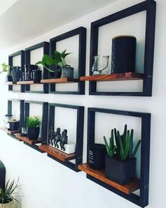 some shelves with plants and other items on them in a room that has white walls