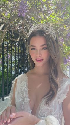 a woman wearing a tiara standing in front of a fence with purple flowers on it