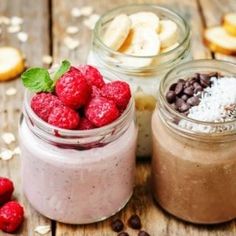 three jars filled with different types of food on top of a wooden table next to spoons