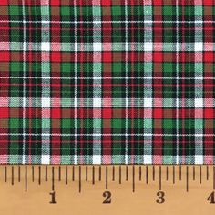 a plaid fabric with red, green and white checks on it's side next to a ruler