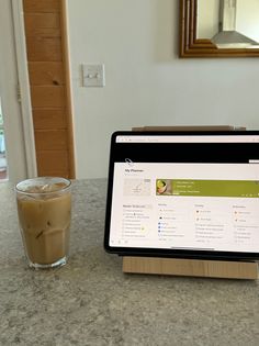 a laptop computer sitting on top of a table next to a cup of coffee