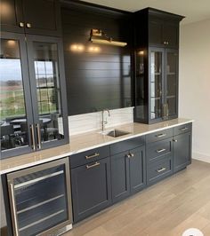 a kitchen with gray cabinets and stainless steel appliances in the center, along with wood flooring