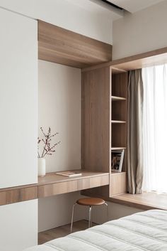 a white bed sitting next to a wooden shelf with a vase on top of it