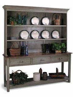 an old style hutch with plates and bowls on the top, sitting in front of a white background