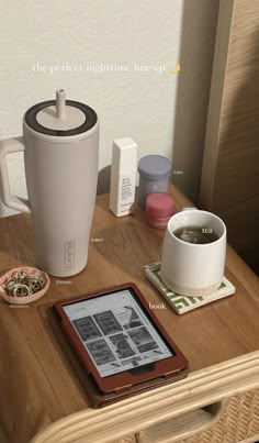 a wooden table topped with a tablet computer next to a cup