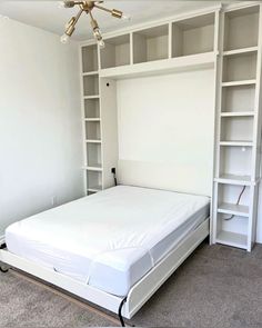 a white bed sitting in a bedroom next to a book shelf