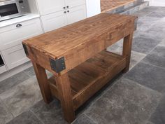 a wooden table sitting in the middle of a kitchen next to a stove top oven