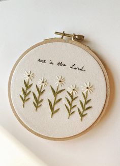 a white embroidered wall hanging with flowers and the words, not in the land on it