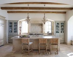 a large kitchen with an island in the middle and two stools at the end