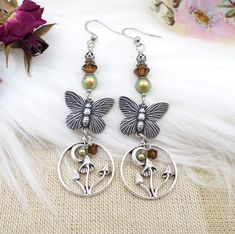 This is my handmade design - earrings made with silver plated butterflies and mushroom crescent moon charms, combined with earthy green pearls and brown crystals!  These cottagecore style earrings are a great gift idea for that special person on your list.  The earrings hang 3 inches total with a 3/4 inch width - ear wires are stainless steel. more of my designs here:  www.etsy.com/shop/hhjewelrydesigns Nickel-free Fairycore Earrings For Jewelry Making, Mushroom Earring, Earrings Fairycore, Butterfly Mushroom, Fairycore Jewelry, Cottagecore Accessories, Brown Crystals, Earthy Green, Cottagecore Style