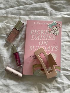 the contents of a pink book and lipstick on a bed