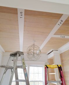 ladders are used to reach the ceiling in this small room with wood paneling