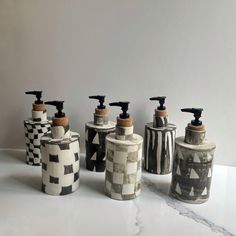 four different types of soap dispensers sitting on a white counter top next to each other