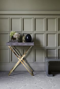 a table with two vases on it in front of a wall and a bench