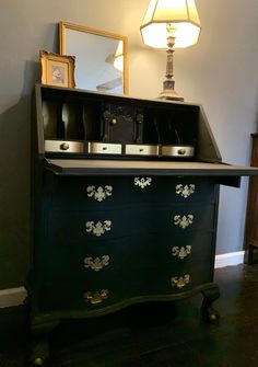 a black dresser with gold accents and a lamp on the side table next to it