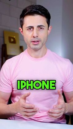 a man wearing a pink shirt with the words iphone in front of him and pointing at his fingers