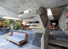 a living room filled with furniture and bookshelves next to a staircase leading up to a second floor