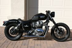 a black motorcycle parked in front of a garage