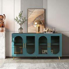 a blue cabinet sitting in front of a white wall next to a vase with a plant