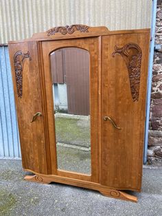 an old wooden armoire with mirrors on the front and back doors, sitting next to a brick wall