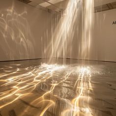 an art installation with water flowing from the ceiling and light shining on the floor in front of it