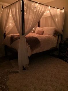 a bed with white curtains and lights on it