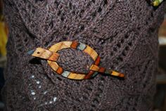 a wooden bird brooch sitting on top of a sweater