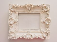 an ornate white photo frame hanging on the wall