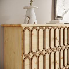 a white vase sitting on top of a wooden cabinet