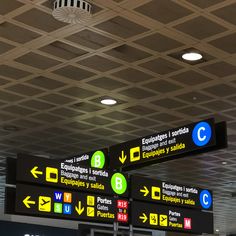 there are many signs on the ceiling in this airport terminal that point to different destinations