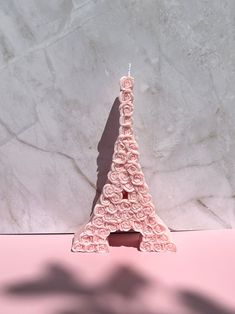 a candle that is shaped like the eiffel tower with pink roses on it