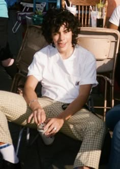 a young man sitting on top of a chair next to a woman in a white shirt