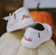 two white tennis shoes sitting on top of a pumpkin with the word mrs and mr written on them