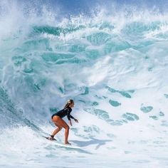 a woman riding a wave on top of a surfboard