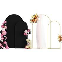 a black and white backdrop with pink flowers on the front, an arch to the back, and a teddy bear next to it