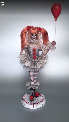 a creepy doll with red hair holding a balloon