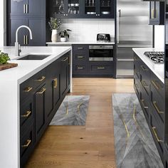 a modern kitchen with black cabinets and white counter tops, gold trim on the handles