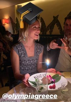 a woman sitting at a table in front of a plate with a cake on it