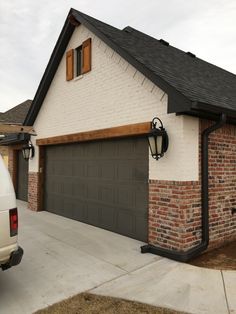 a white truck is parked in front of a brick and stucco house with two garage doors