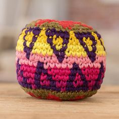 a colorful crocheted cushion sitting on top of a wooden table