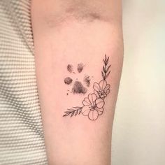 a black and white flower tattoo on the right arm, with paw prints in the background